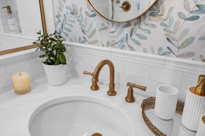 Brass widespread faucet with lever handles on a white quartz vanity top and an oval undermount sink