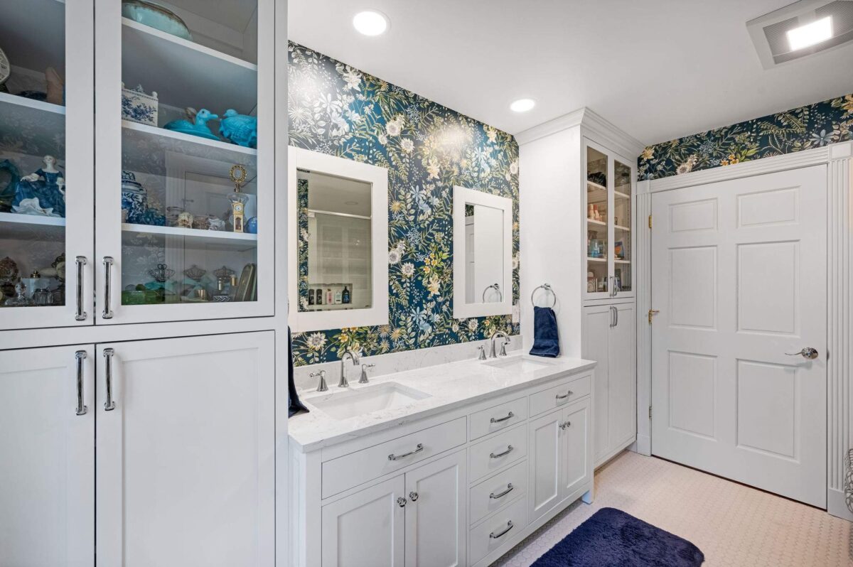 Bathroom with a white double vanity, two rectangular undermount sinks and chrome faucets under floral wallpaper