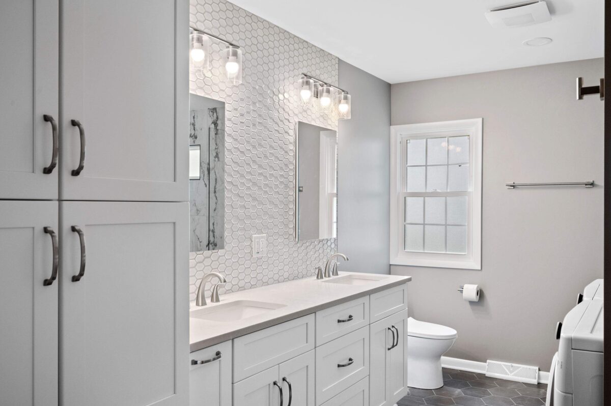Bathroom with a white double vanity, two rectangular undermount sinks, brushed nickel faucets and a hexagon tile wall