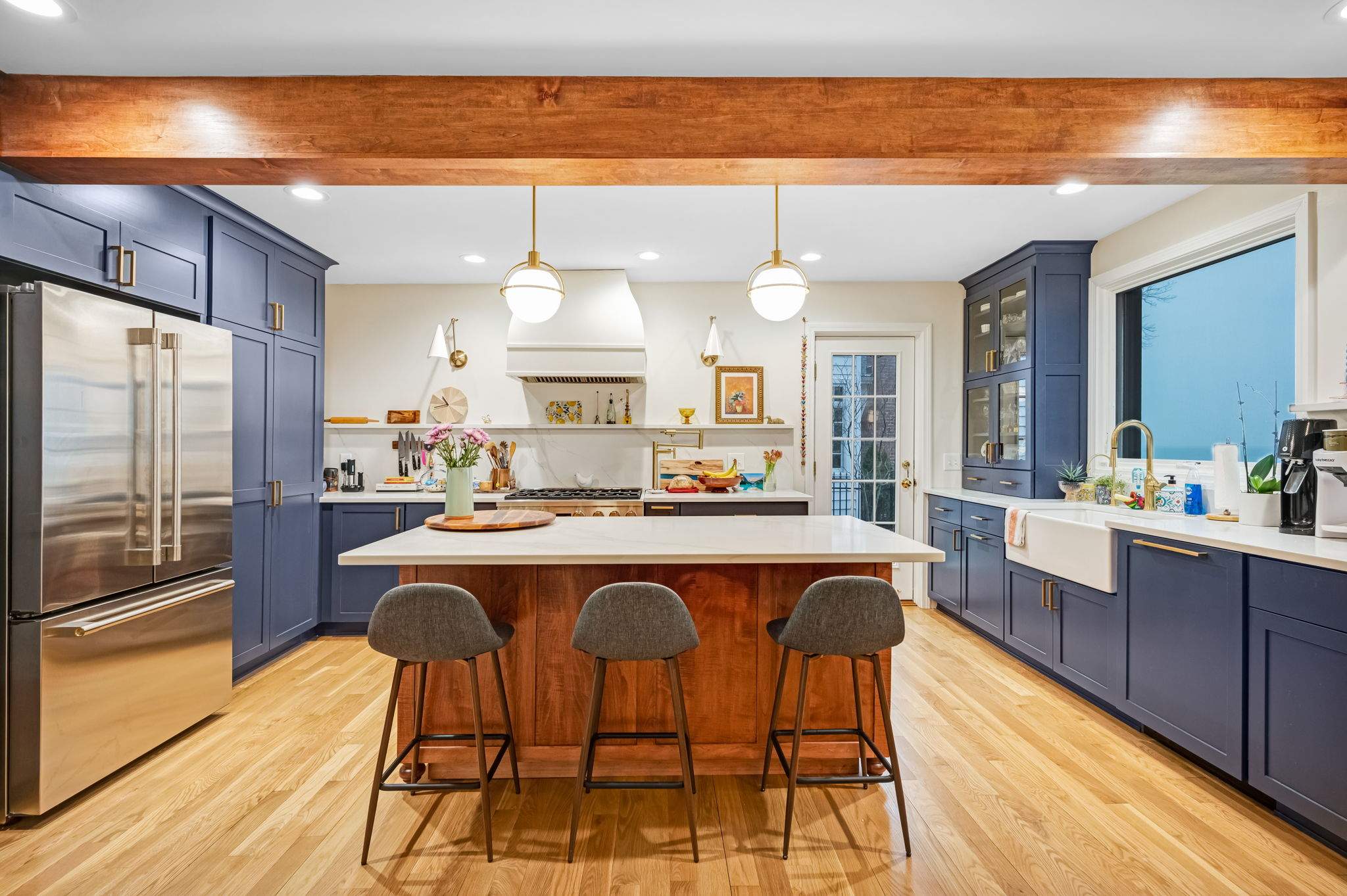 Navy kitchen with wood beam, island and farmhouse sink