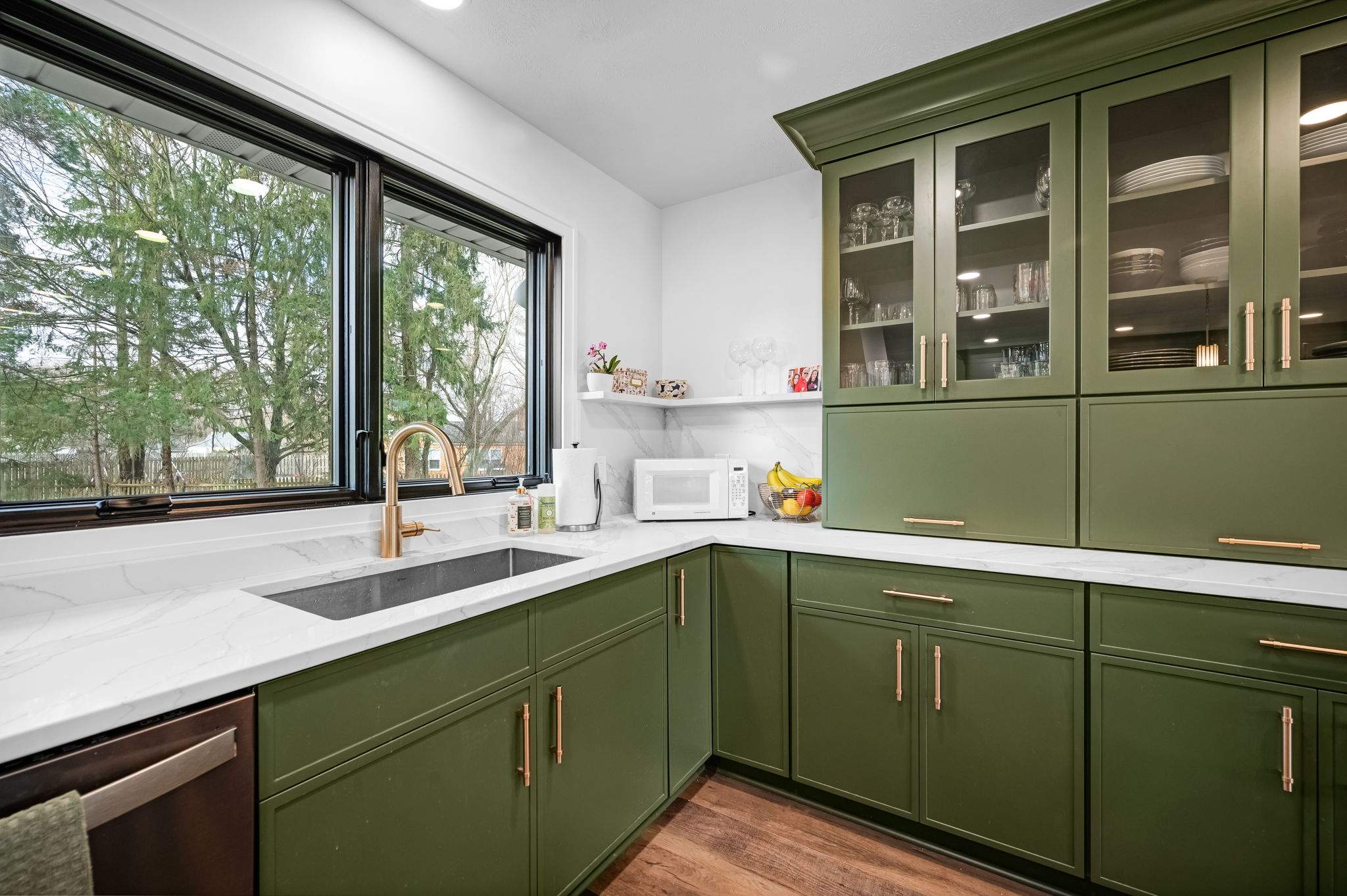 Green kitchen with a stainless steel sink under a large window